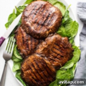 Grilled mushrooms on a plate with spinach and a fork, showing perfect char.