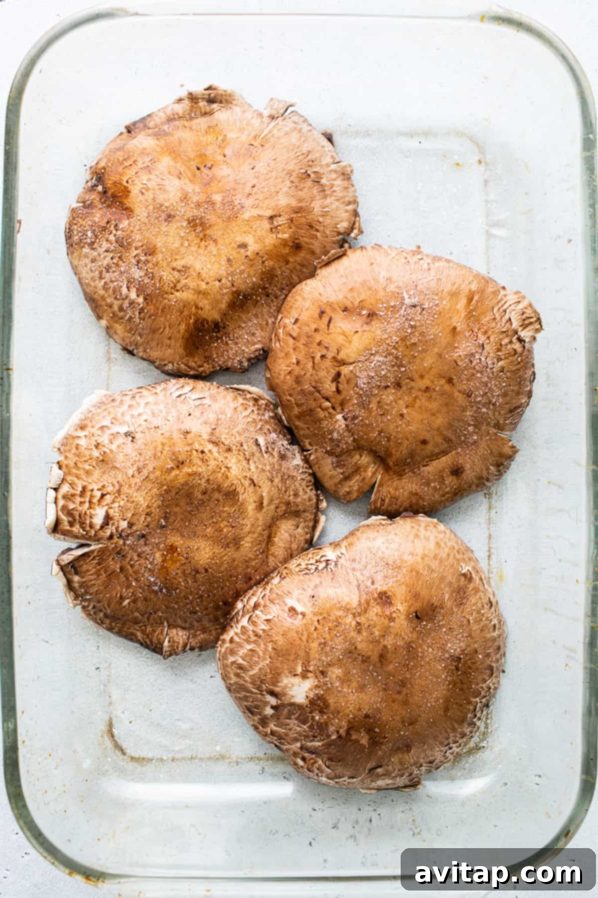 Large portobello mushrooms beautifully arranged in a baking dish, ready for marinating, promising rich flavors.