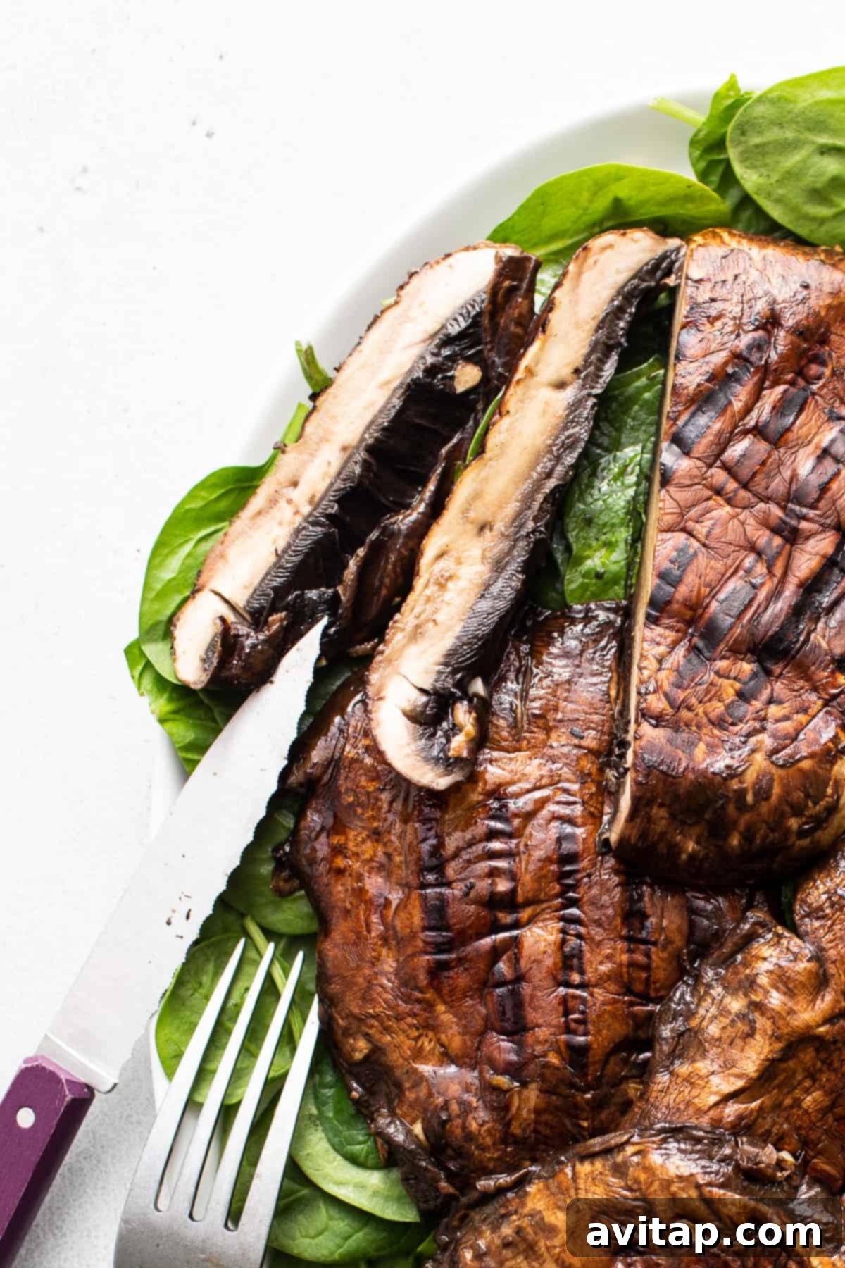 A perfectly sliced grilled portobello mushroom on a plate, revealing its juicy, tender interior and rich color.