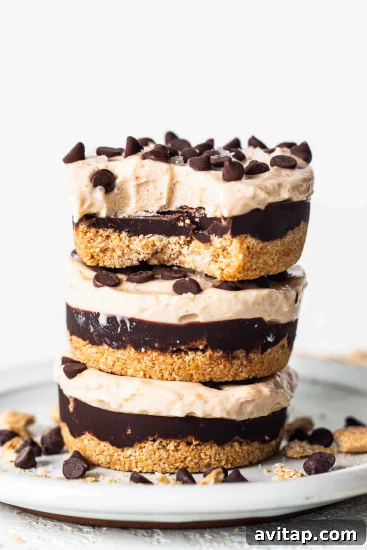 Stacked peanut butter chocolate cheesecake cups on a white plate, highlighting their creamy texture and chocolate topping.