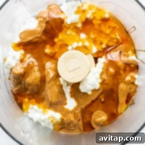 A food processor filled with a creamy mixture of cottage cheese, peanut butter, and honey.
