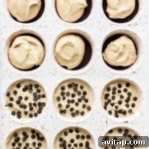 Assembled peanut butter chocolate cheesecake cups in a muffin pan before freezing, topped with mini chocolate chips.
