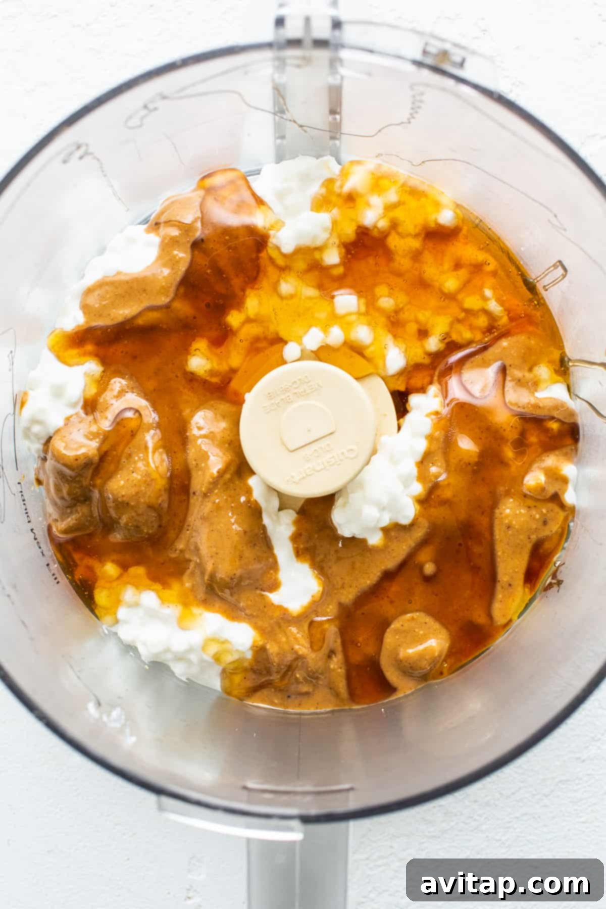 A food processor bowl containing cottage cheese, peanut butter, and honey, ready to be blended into a creamy filling.