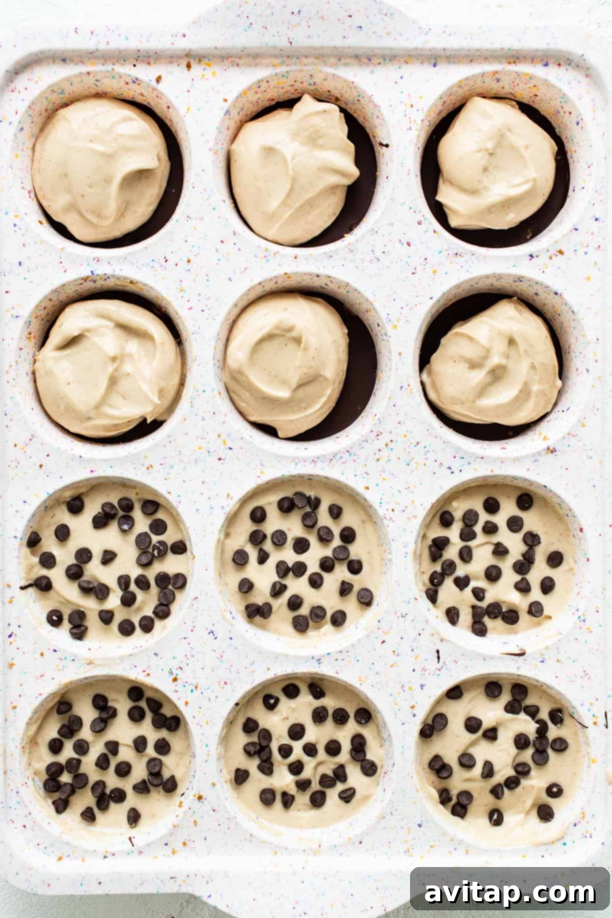 Peanut butter chocolate cheesecake cups set in a muffin tin, ready for freezing.
