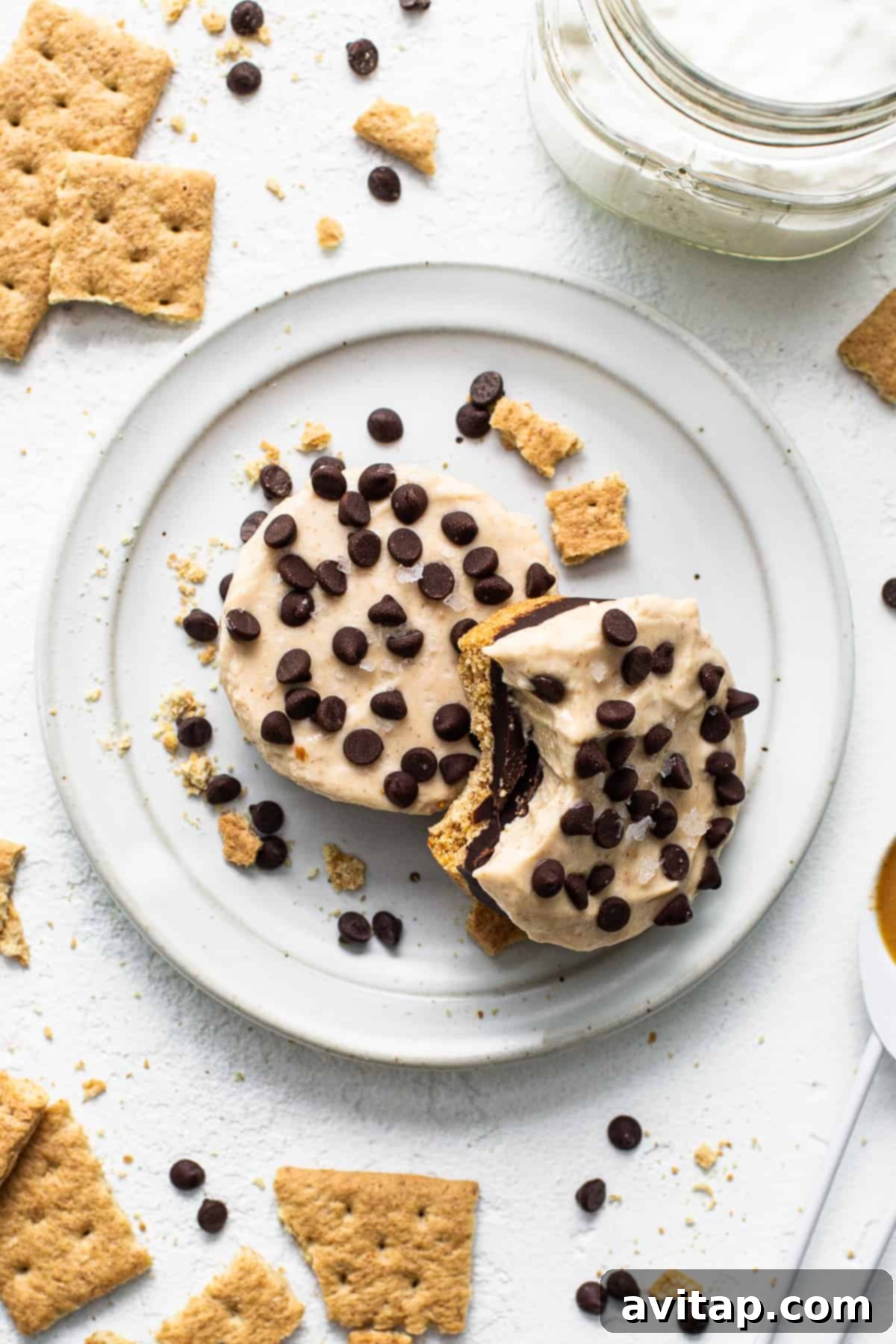 A peanut butter chocolate cheesecake cup on a plate with a bite taken out, showing the layers.