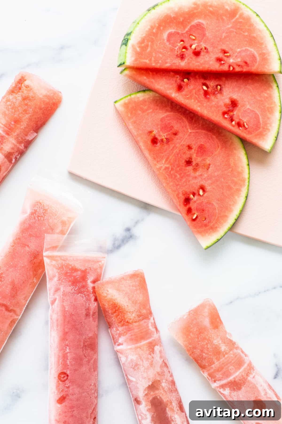 Vibrant watermelon wine freeze pops displayed attractively on a wooden table, ready for a summer celebration.