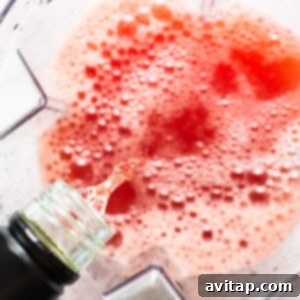 Pouring white wine into a blender filled with watermelon juice and simple syrup.