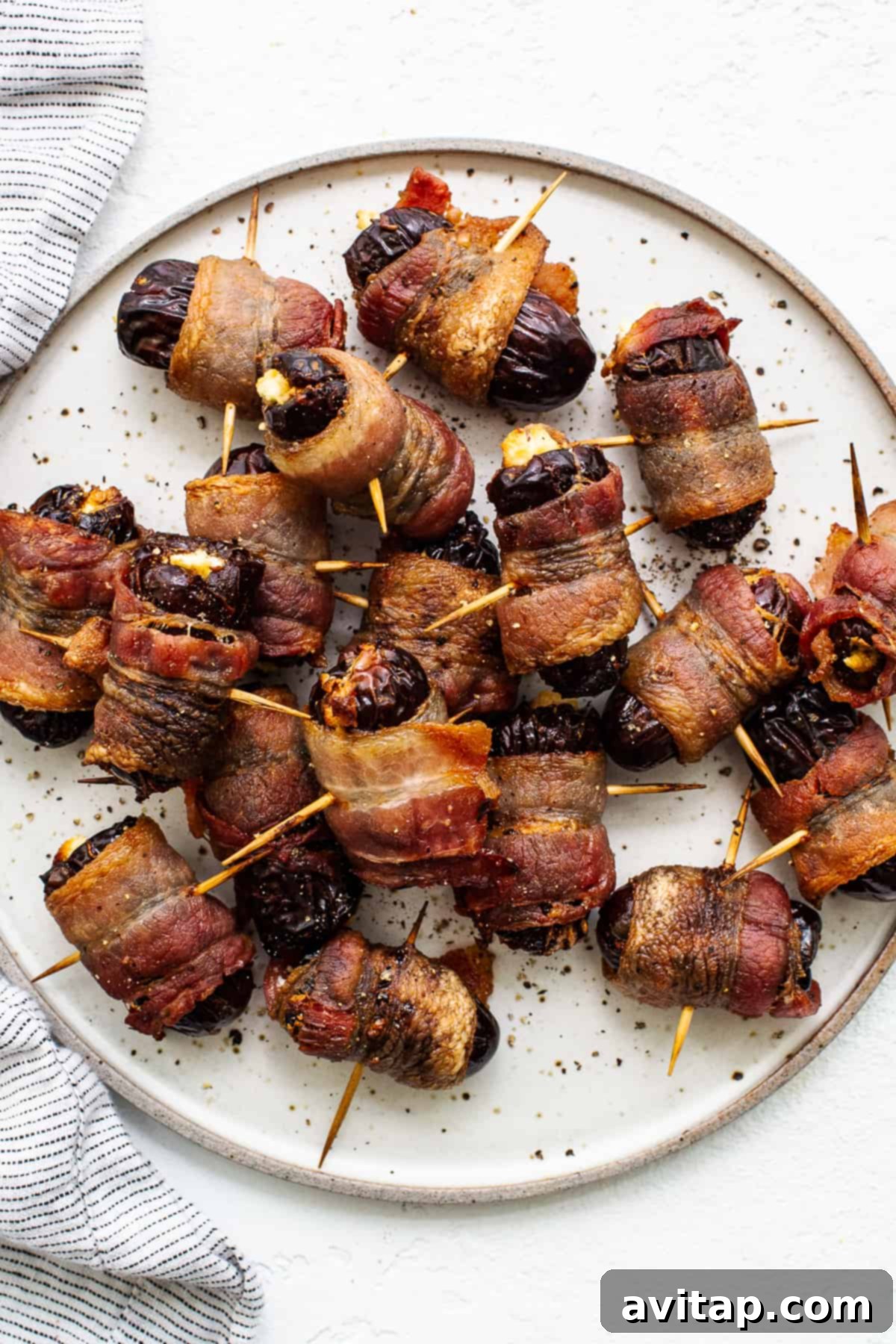 Bacon wrapped dates with goat cheese on a plate, ready to serve.