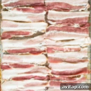 Sliced bacon on a baking sheet, par-baking.