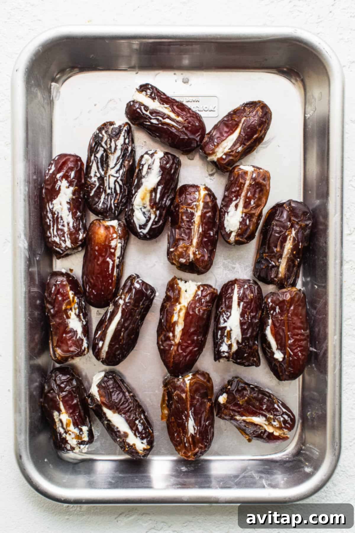 Dates stuffed with goat cheese on a baking sheet before wrapping with bacon.