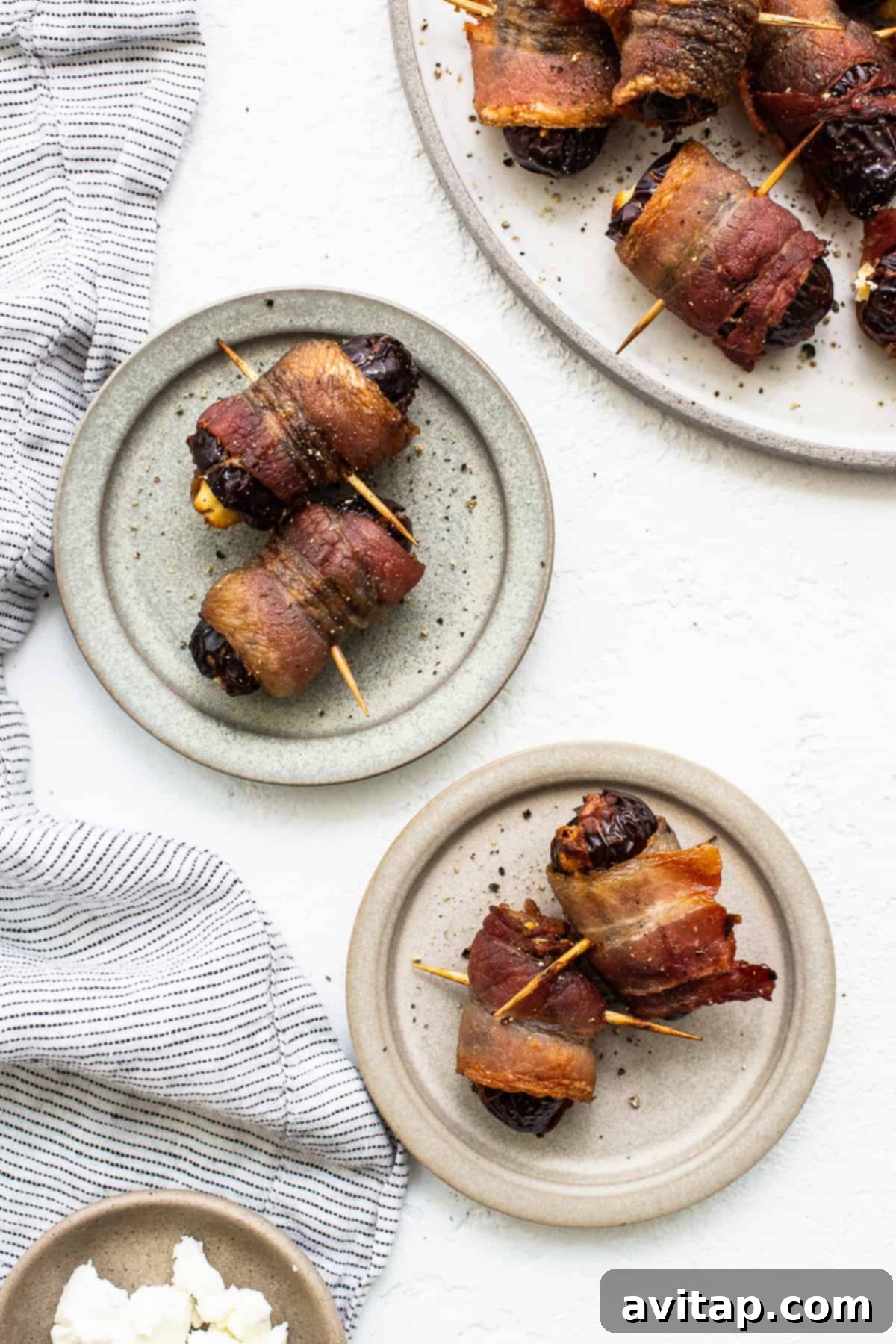 Bacon wrapped dates with goat cheese on a wooden board.