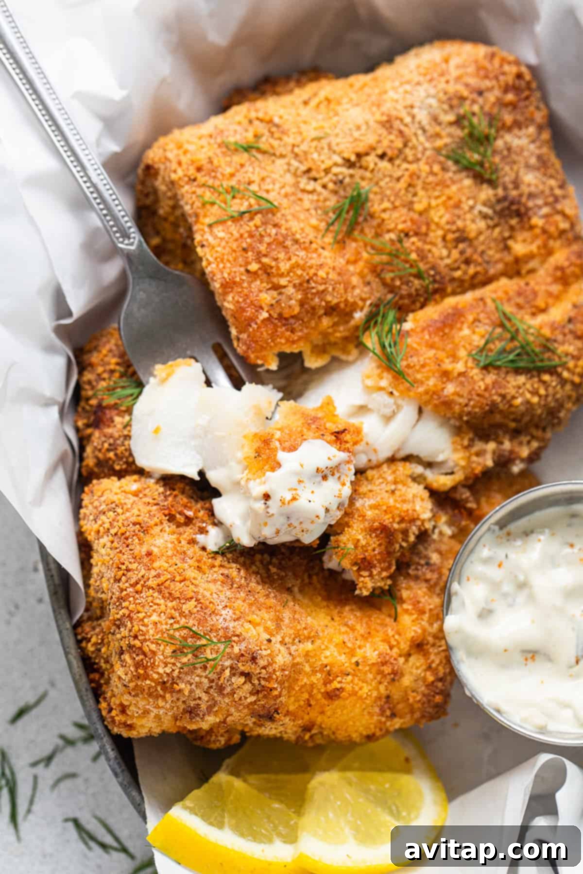 Crispy air fryer fish in a basket with tartar sauce.