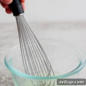 Whisking fish marinade in a bowl, showing the liquids combining.