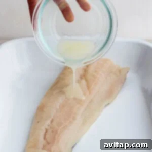 Marinade being poured over a fish filet in a baking dish.