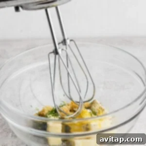 Grilled fish marinade being mixed together in a bowl with a hand mixer, showing the creamy texture.