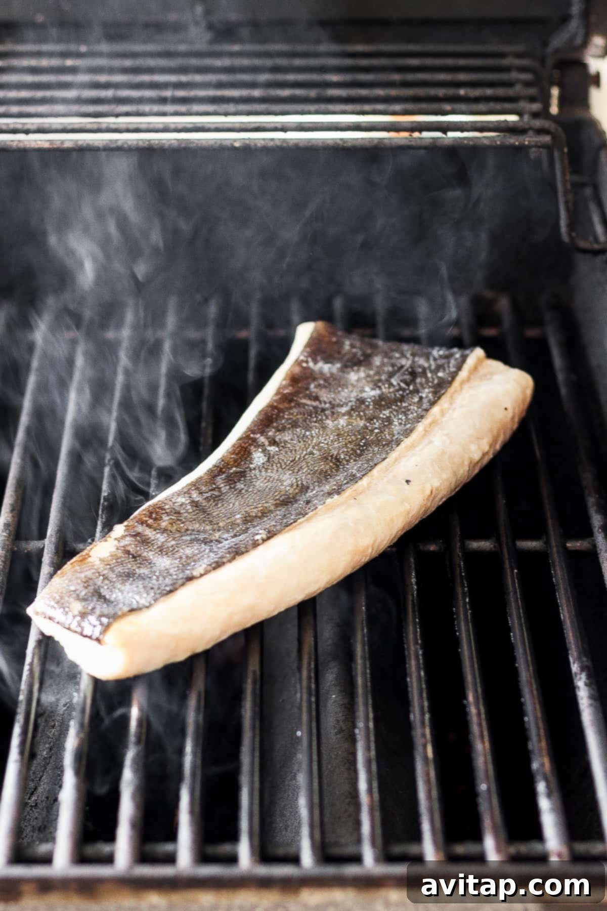 A beautiful filet of white fish perfectly searing on a hot grill.