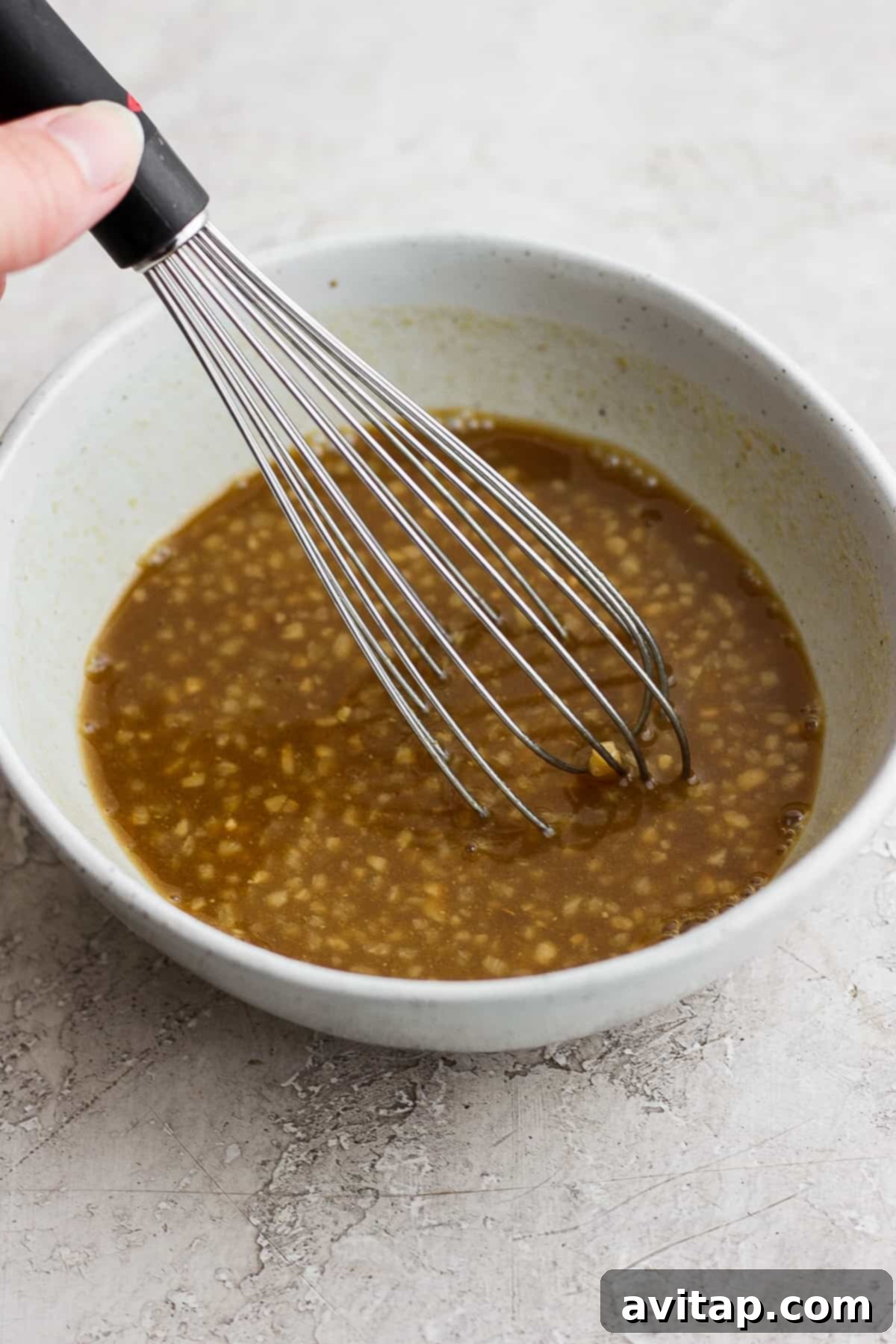 Rib marinade ingredients in a bowl with a whisk, showing the smooth, emulsified texture.