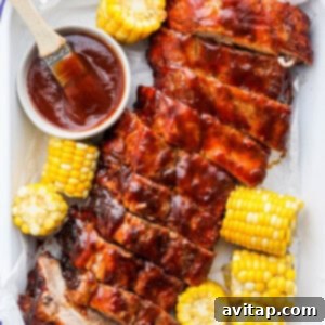 Grilled baby back ribs served with corn on the cob, garnished with fresh herbs and BBQ sauce.