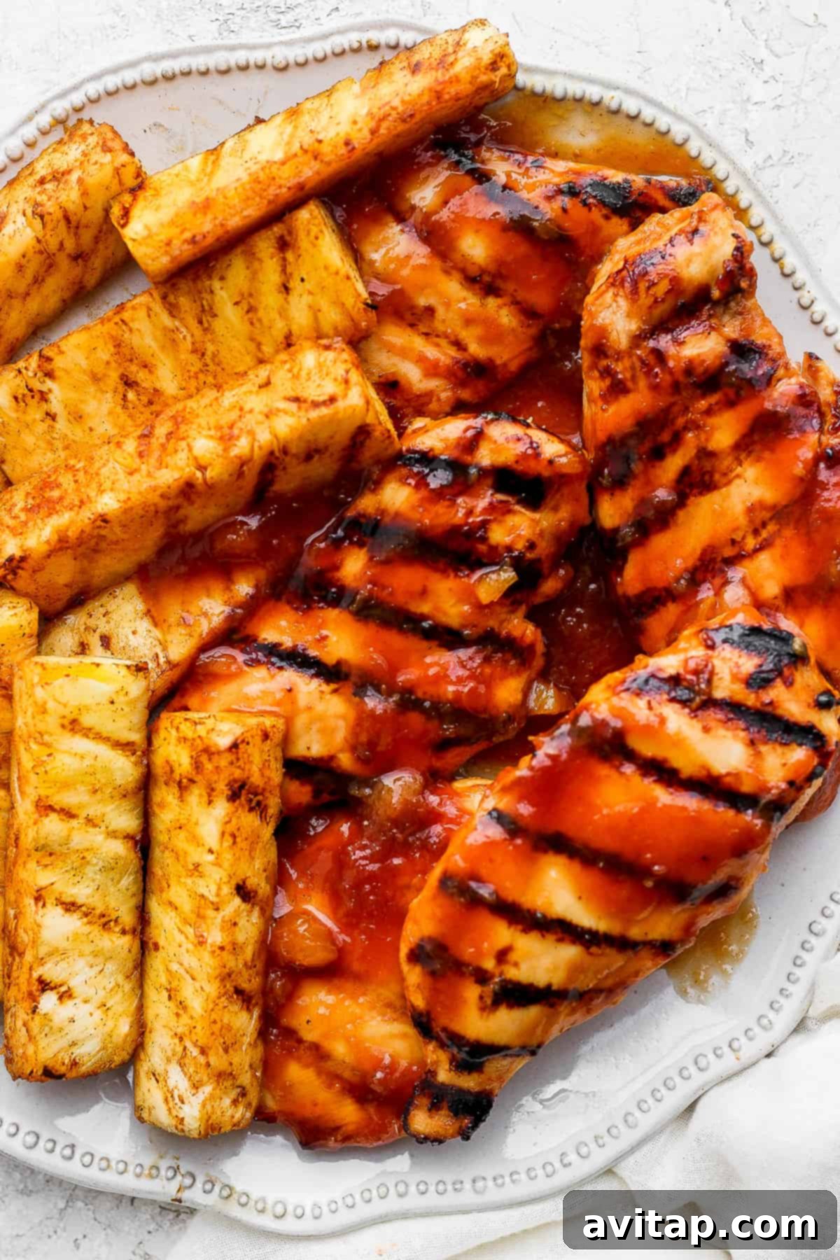A beautifully plated dish of grilled chicken and pineapple on a white plate, ready to be served.