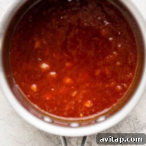 A pot filled with red sauce on top of a counter.