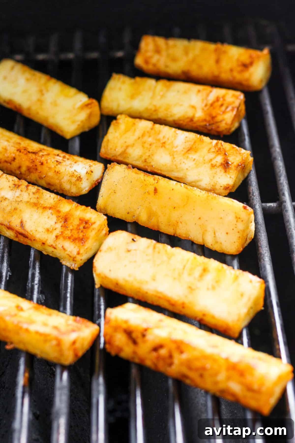 A close-up view of chicken breasts and pineapple slices sizzling on a hot grill, showing perfect grill marks.