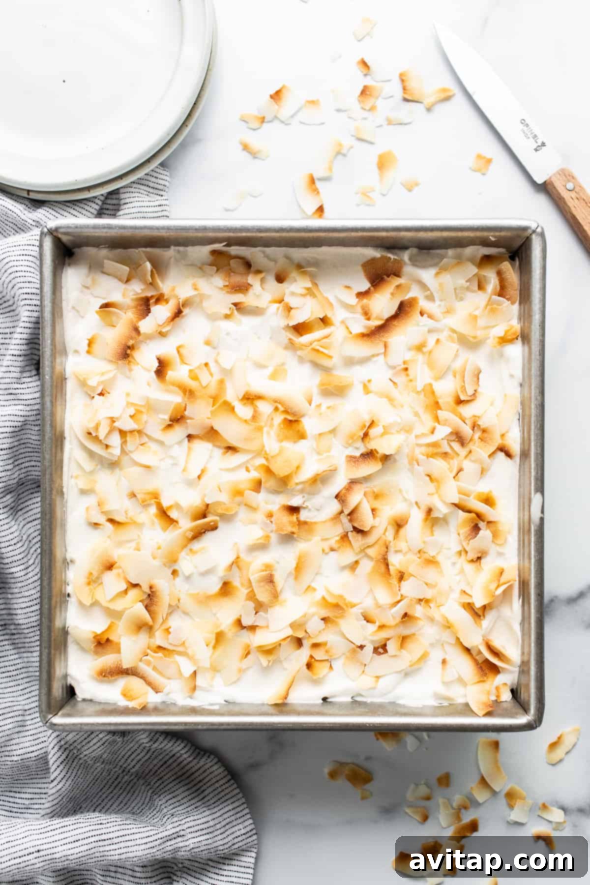 A full pan of golden-brown coconut cream pie bars, generously topped with toasted coconut flakes, ready to be enjoyed.