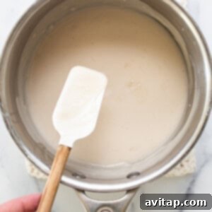 A person holding a spatula in a saucepan.