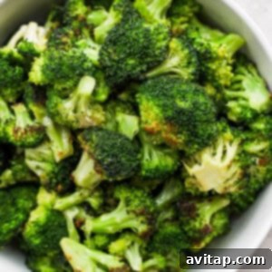 A white bowl filled with grilled broccoli on top of a table.