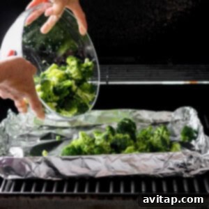 A person is carefully placing seasoned broccoli florets onto the hot grill.