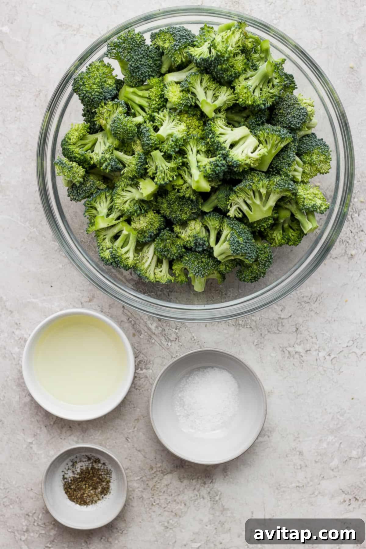 A bowl of freshly grilled broccoli florets with two smaller bowls of dipping sauce on a table, ready to be served.