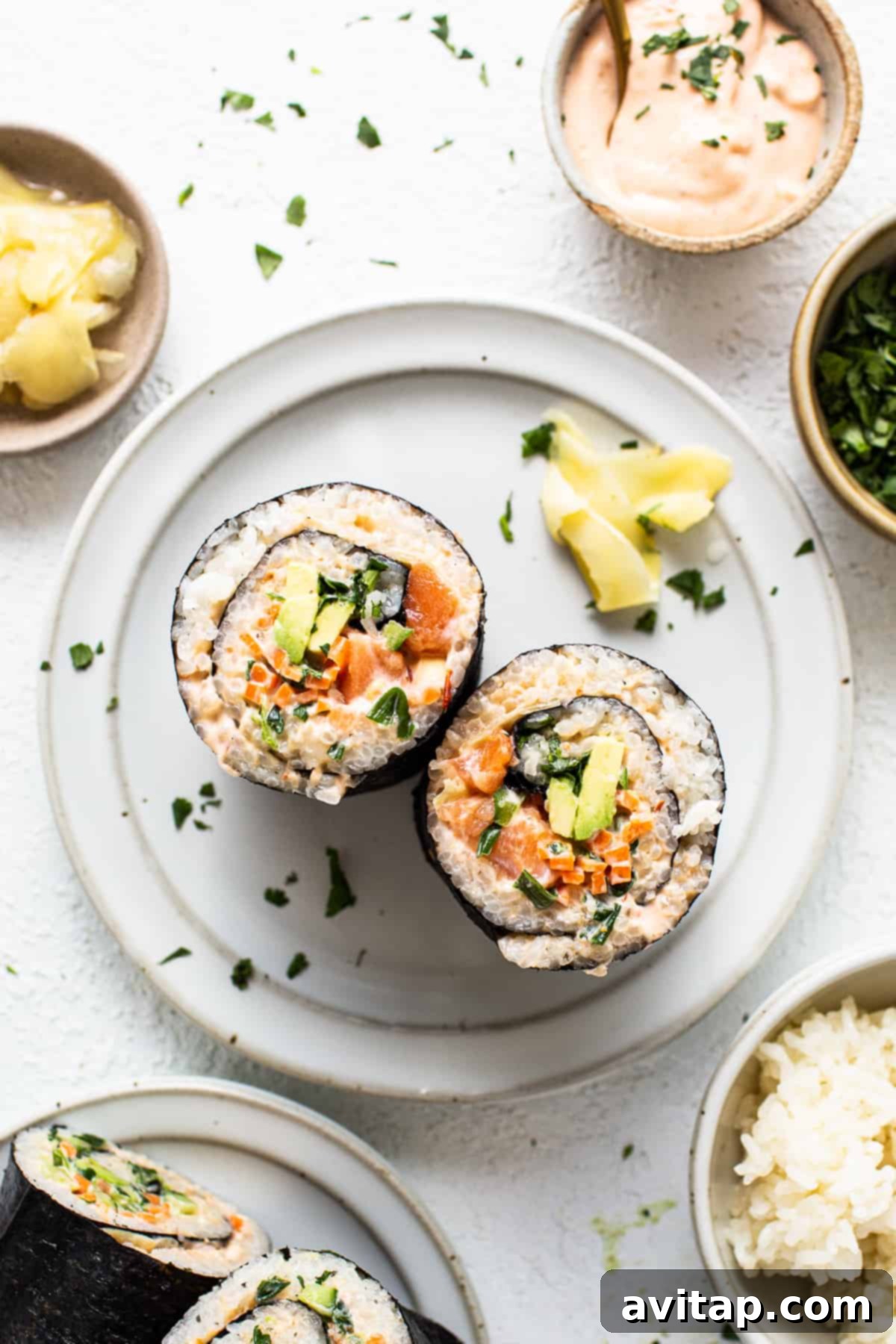 A pristine white plate holding artfully crafted sushi alongside neat bowls of fluffy rice, indicating a fresh and inviting meal.