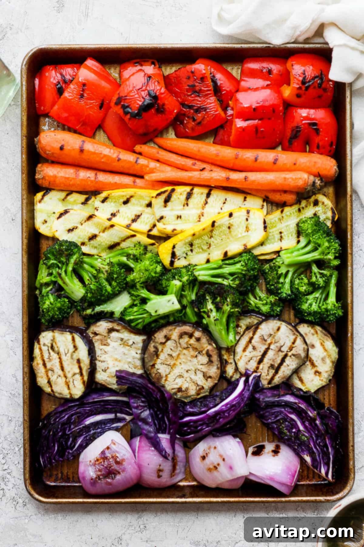A vibrant tray of grilled vegetables, including carrots, broccoli, and red onions, showcasing their charred marks.