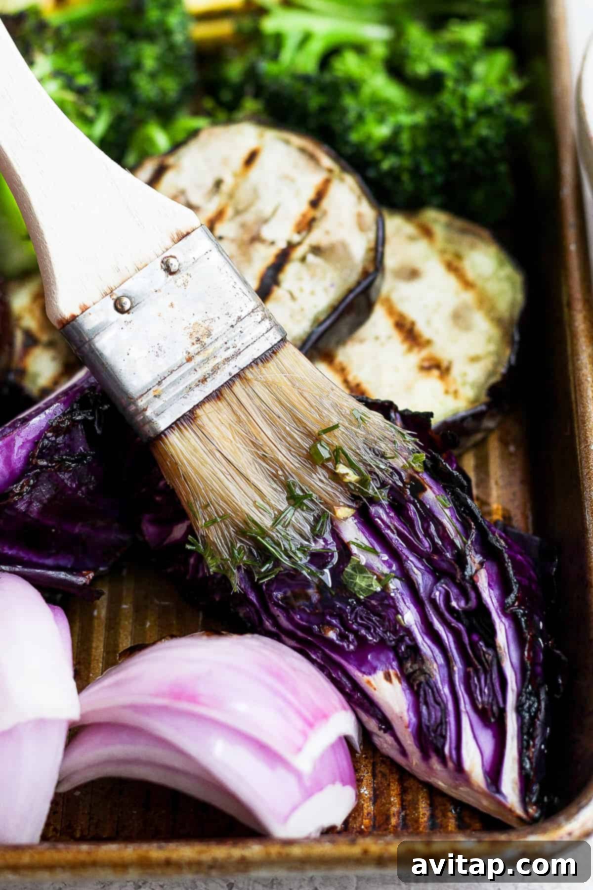 A close-up of a pastry brush coated with the vibrant herb marinade, ready to baste grilled vegetables.