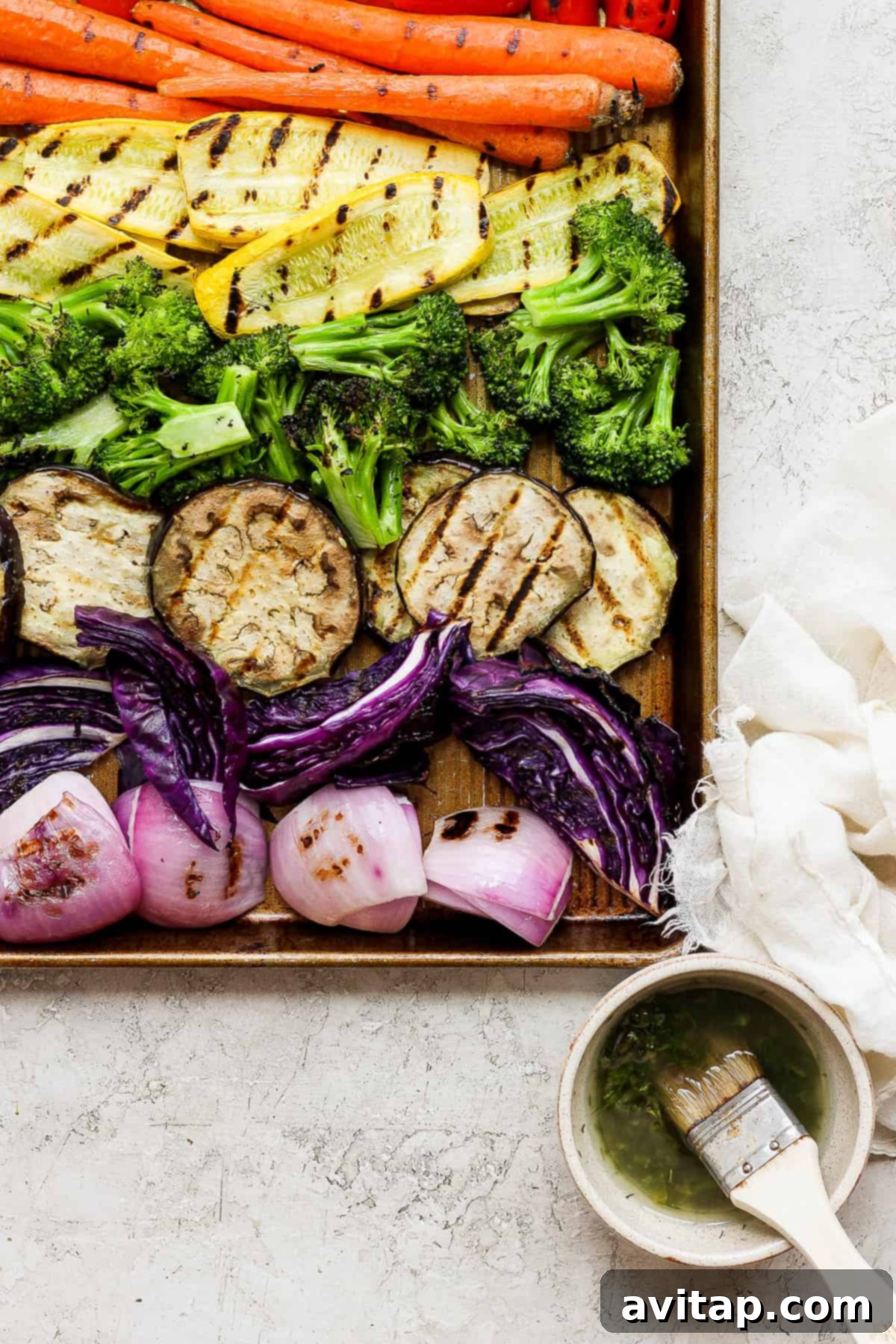 A tray of vibrant grilled vegetables served alongside a bowl of fresh soup, showcasing a balanced meal.