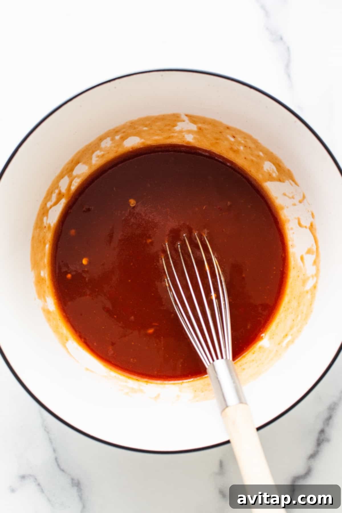 Firecracker sauce freshly mixed in a bowl with a whisk, showing its smooth consistency.