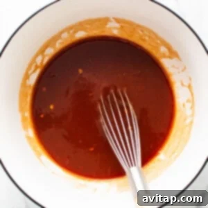 bbq sauce in a bowl with a whisk, showing the smooth mixing process.