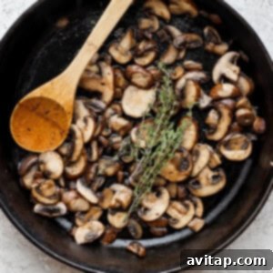 Effortless Sautéed Mushrooms 11 Sautéed mushrooms in a skillet with a wooden spoon, showing the moisture release.