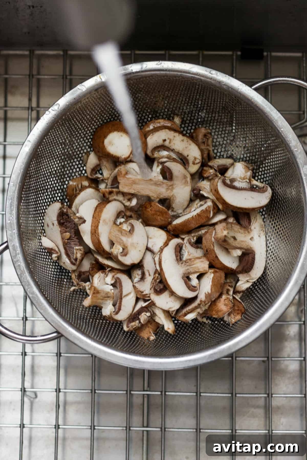 Effortless Sautéed Mushrooms 4 Cleaned mushrooms resting in a strainer on a cooling rack, showing their readiness for cooking.