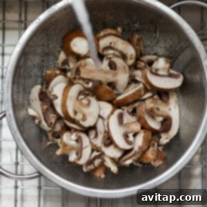 Effortless Sautéed Mushrooms 9 Mushrooms in a strainer on a cooling rack, freshly cleaned.