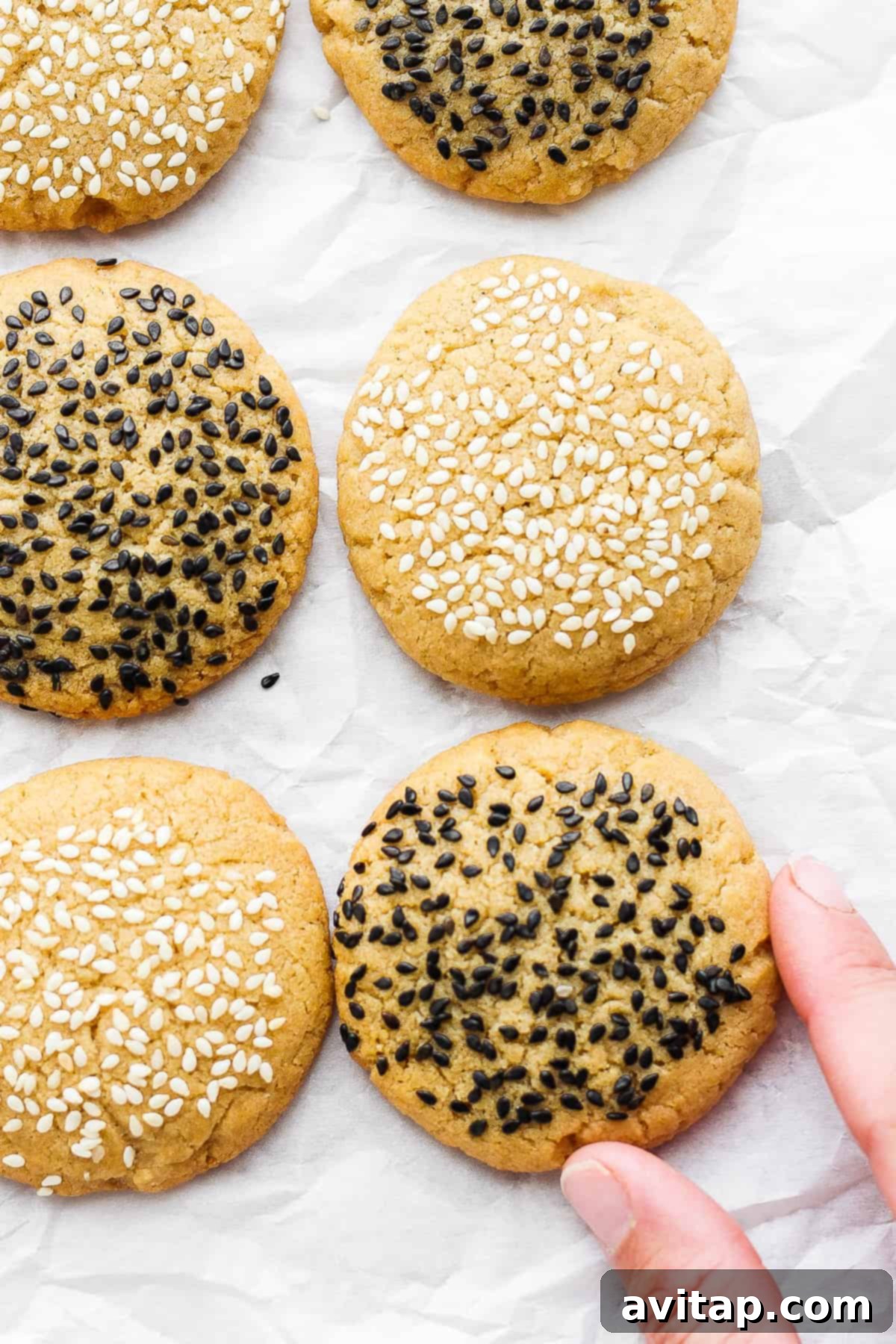 A perfectly baked tahini cookie, showcasing its golden-brown color and a generous sprinkling of sesame seeds.