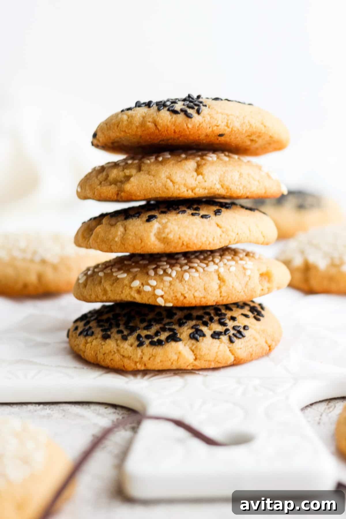 A perfectly stacked pile of tahini cookies, garnished with sesame seeds, ready to be devoured.