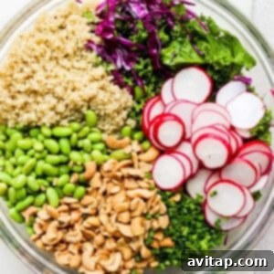 A bowl filled with greens, radishes, and quinoa, ready for dressing.