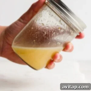 A person holding a jar with lemon juice and other dressing ingredients.