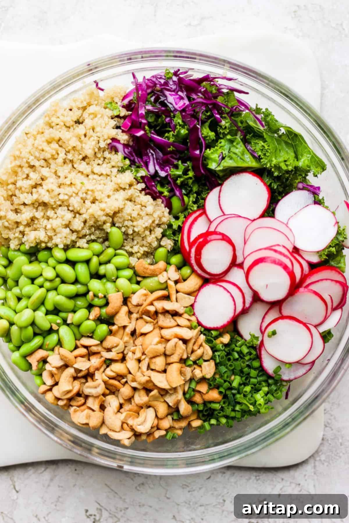 A vibrant bowl filled with massaged kale, thinly sliced radishes, and fluffy quinoa, ready for additional ingredients.
