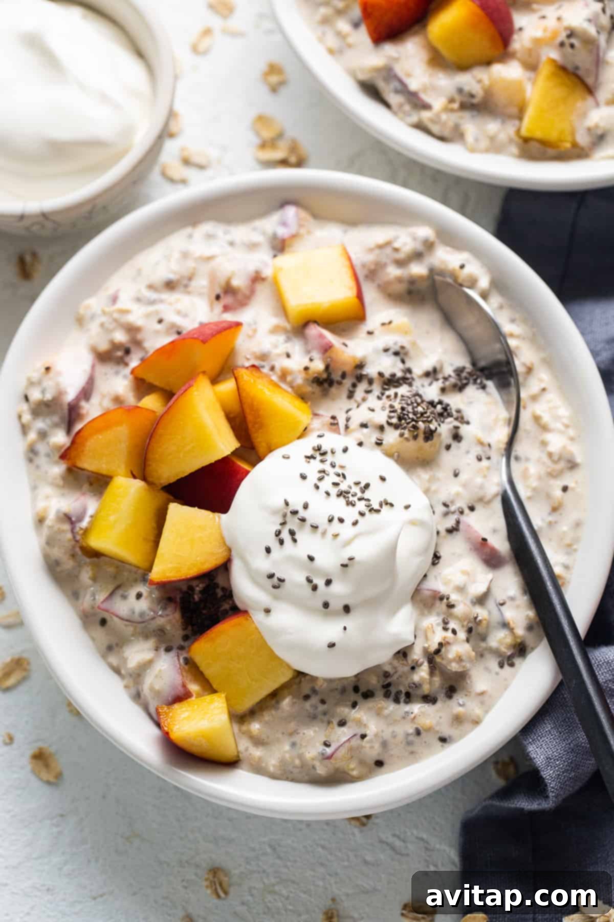 Dreamy Peach Overnight Oats 2 A beautiful bowl of peaches and cream overnight oats topped with fresh peach slices and a dollop of cream, ready to eat.