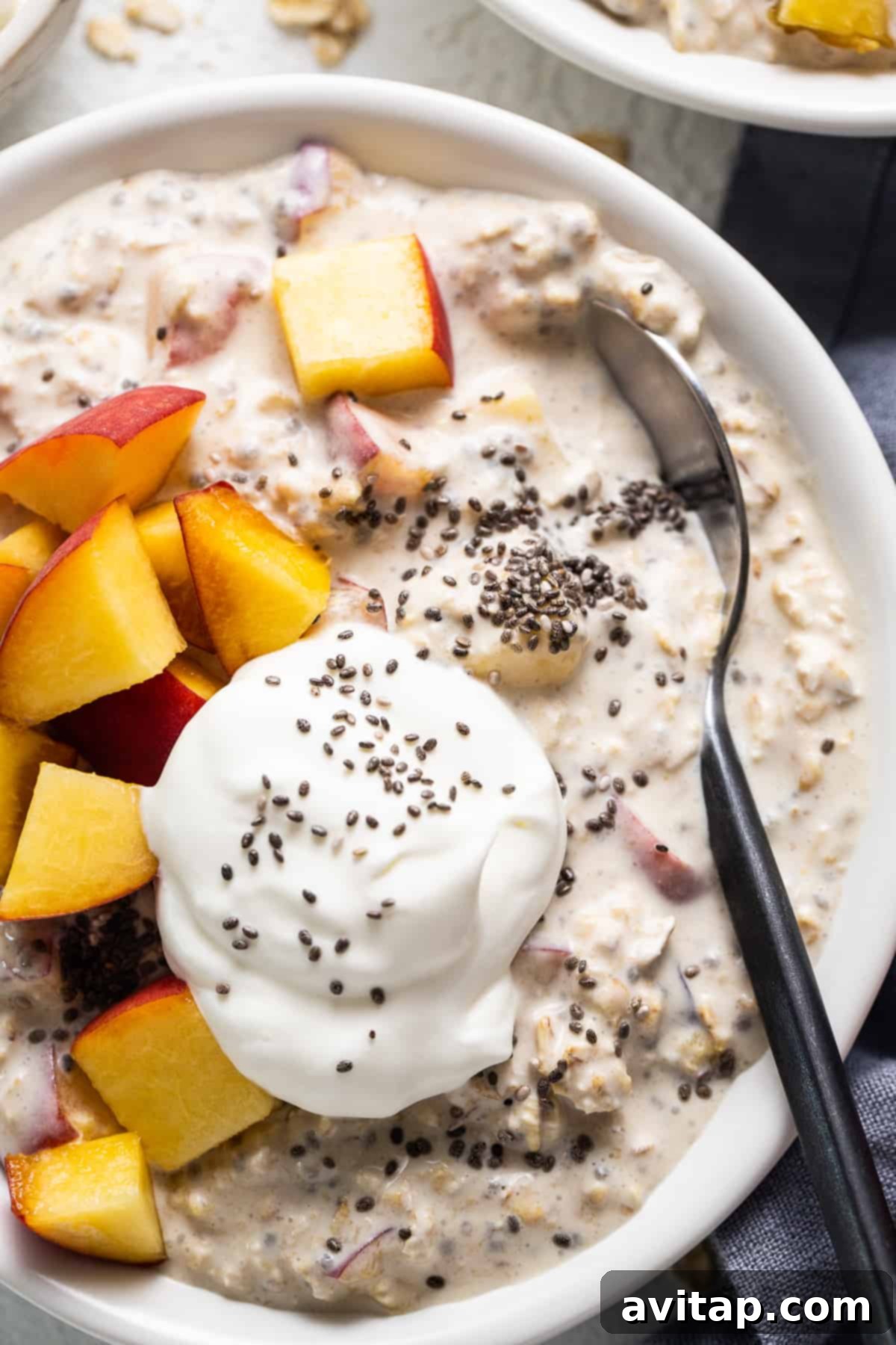 Dreamy Peach Overnight Oats 6 A close-up of a spoon scooping a generous portion of peaches and cream overnight oats, showing the creamy texture and peach chunks.