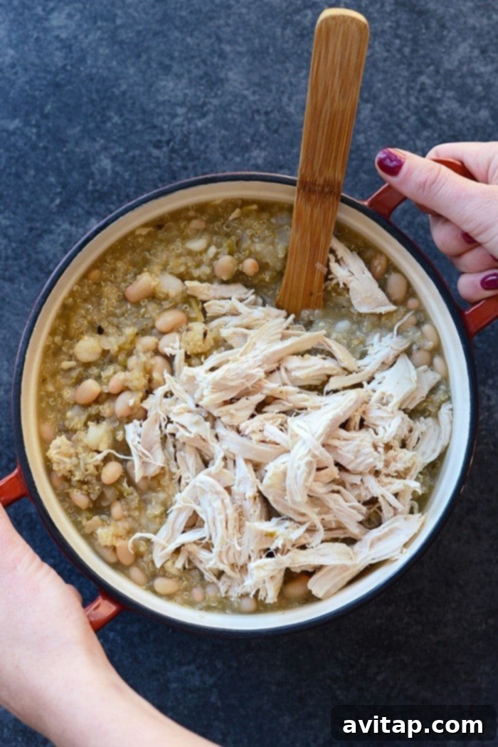 A close-up of the rich and creamy texture of the White Chicken Quinoa Chili, showing visible pieces of chicken, white beans, and quinoa, ready to be enjoyed as a hearty meal.