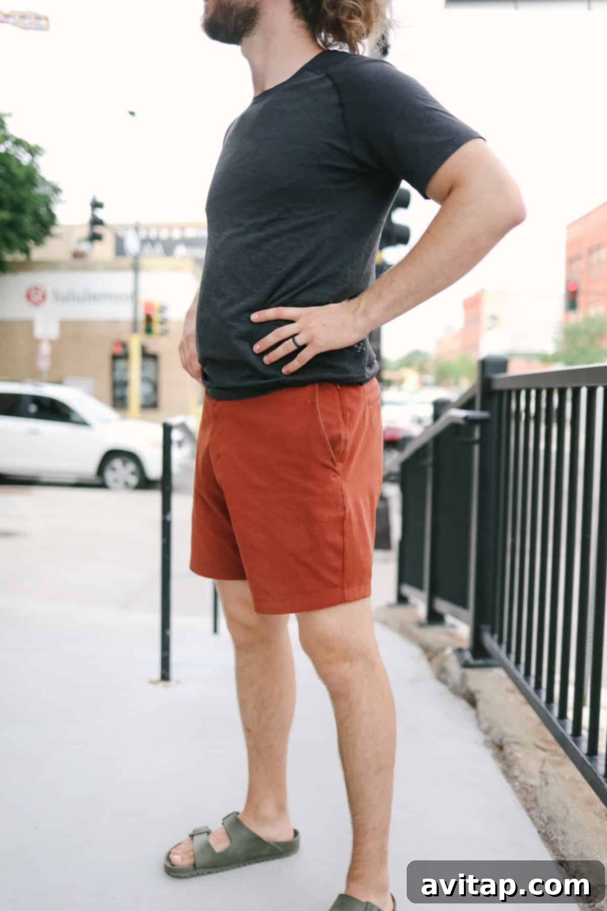A man in Lululemon New Venture shorts standing casually on a sidewalk, hands on hips, showcasing the relaxed fit.