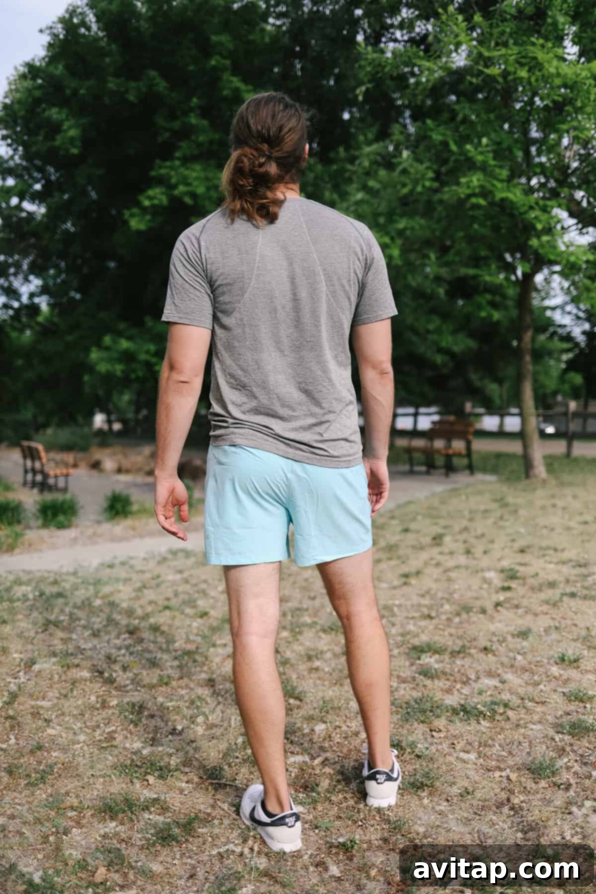 A man in Lululemon Pace Breaker shorts stands confidently in a scenic field, ready for action.