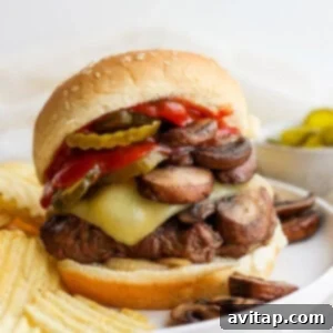 A delicious burger featuring mushrooms, cheese, and pickles, beautifully presented on a plate.